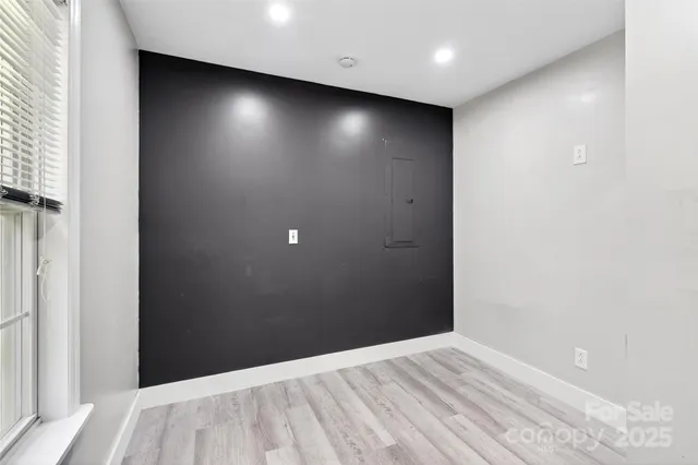 an empty room with wooden floor closet and windows