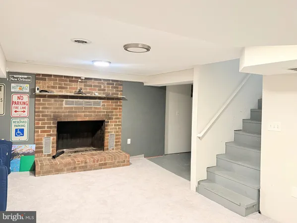 a view of an empty room with wooden floor fireplace and a window