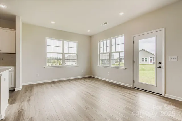 a view of an empty room with window and wooden floor