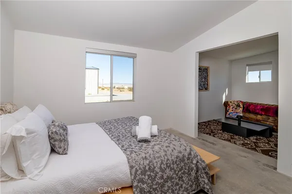 a bed sitting in a bedroom next to a window with a potted plant on a table