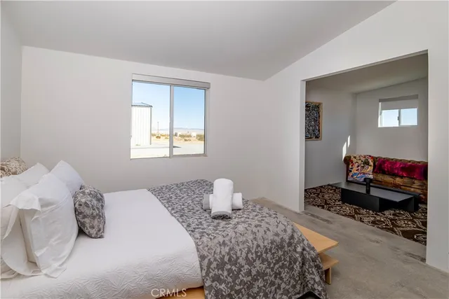 a bed sitting in a bedroom next to a window with a potted plant on a table