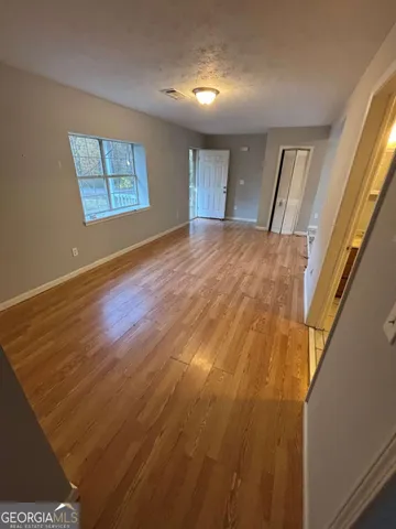 a view of an empty room with wooden floor and a window