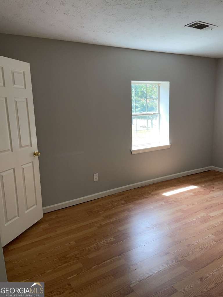 1759 Teamon Road, Unit B Griffin, GA 30223 - Photo 6 of 10 an empty room with wooden floor and windows