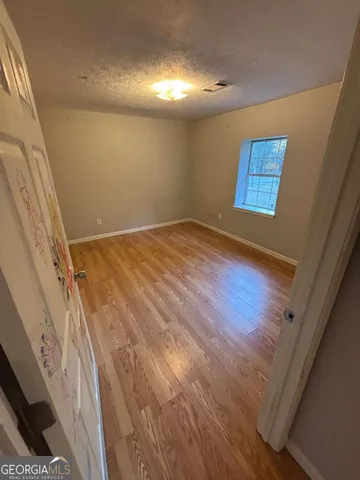 a view of empty room with wooden floor