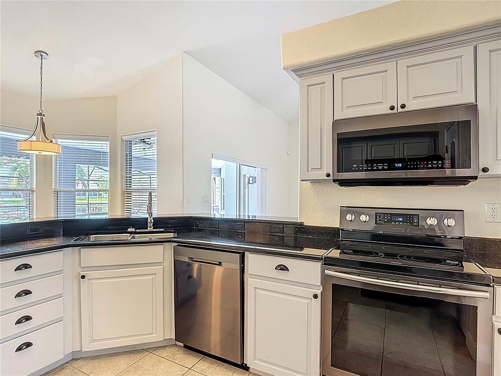 3189 Bayview Lane St. Cloud, FL 34772 - Photo 16 of 41 a kitchen with granite countertop a sink a stove and microwave