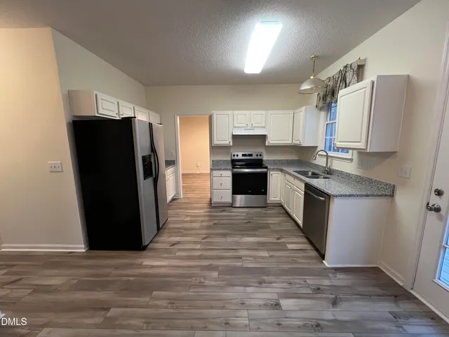 a kitchen with stainless steel appliances granite countertop a refrigerator stove and sink