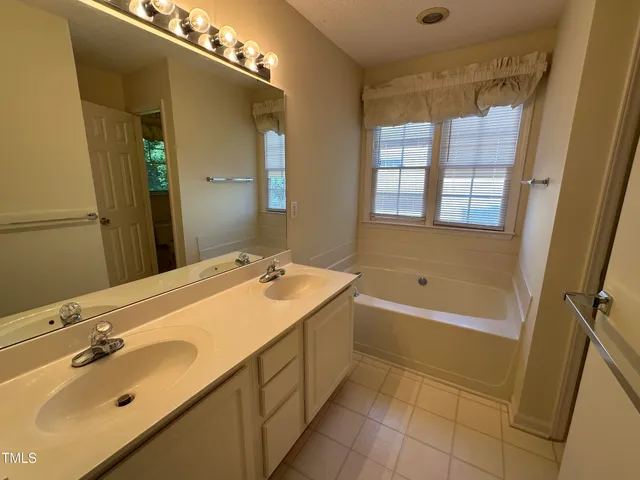 a bathroom with a tub sink and mirror