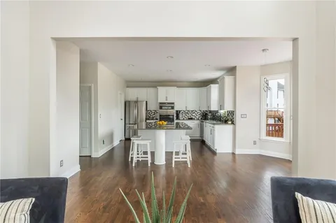 a kitchen with stainless steel appliances granite countertop a stove a sink and white cabinets with wooden floor