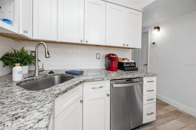 a kitchen with granite countertop a sink stove and cabinets