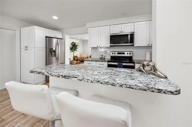 a living room with stainless steel appliances granite countertop a stove a microwave a sink and a refrigerator