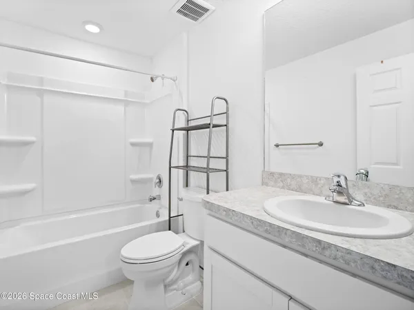 an empty room with wooden floor ceiling fan and windows