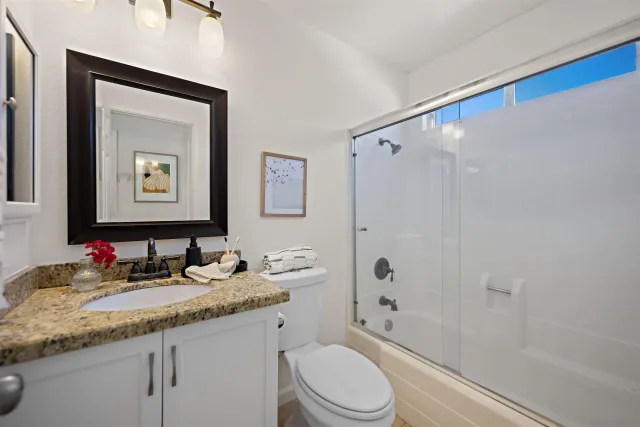a bathroom with a granite countertop sink toilet and shower