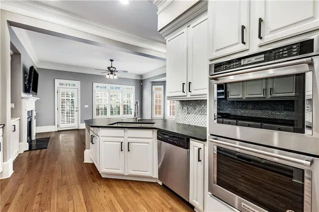 a kitchen with stainless steel appliances white cabinets and wooden floor