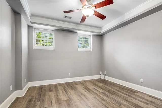 an empty room with wooden floor chandelier fan and windows