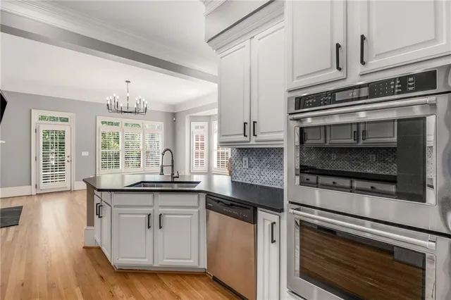 a kitchen with granite countertop white cabinets and stainless steel appliances