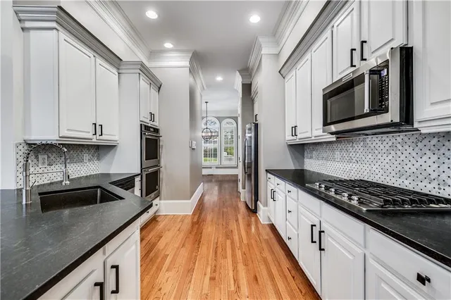 a kitchen with stainless steel appliances granite countertop a stove a sink and a microwave
