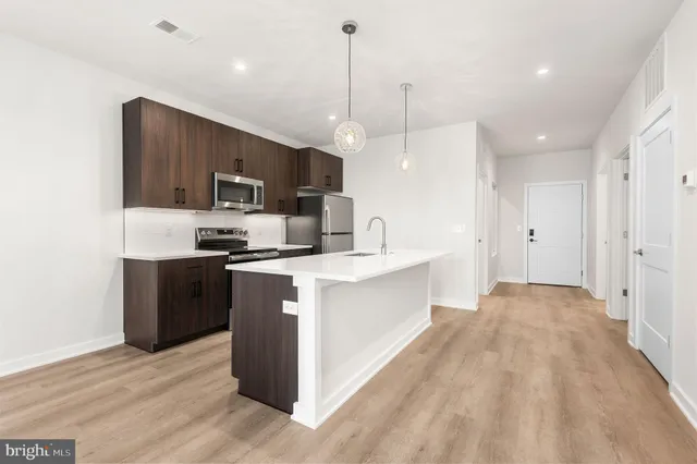 a large kitchen with kitchen island a sink a counter space stainless steel appliances and cabinets