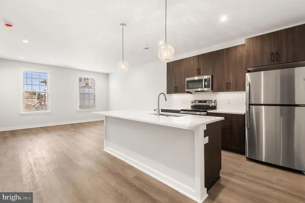 a kitchen with stainless steel appliances granite countertop a refrigerator a stove a sink dishwasher and a refrigerator with wooden floor
