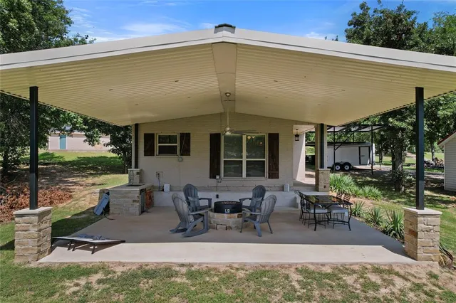 a view of a patio with table and chairs potted plants and a large tree