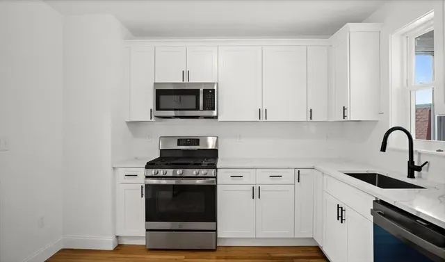 a kitchen with white cabinets and stainless steel appliances