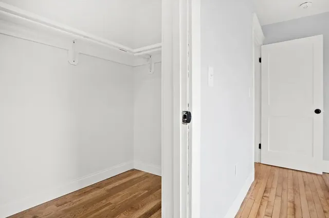 a view of hallway with closet and wooden floor