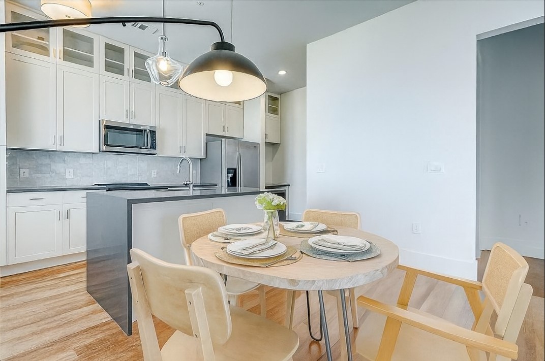 a kitchen with stainless steel appliances granite countertop a sink a stove a dining table and chairs with wooden floor