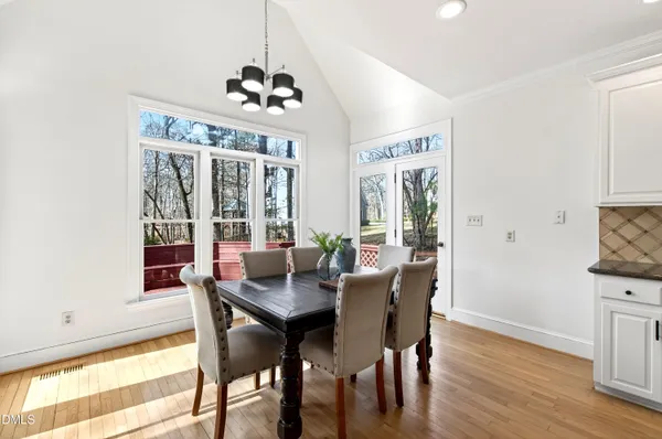 a kitchen with granite countertop a stove a sink a dining table and chairs with wooden floor