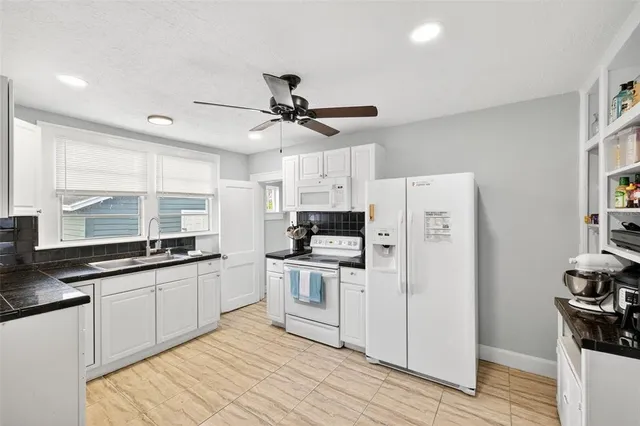 a kitchen with stainless steel appliances a sink a stove a refrigerator cabinets and wooden floor