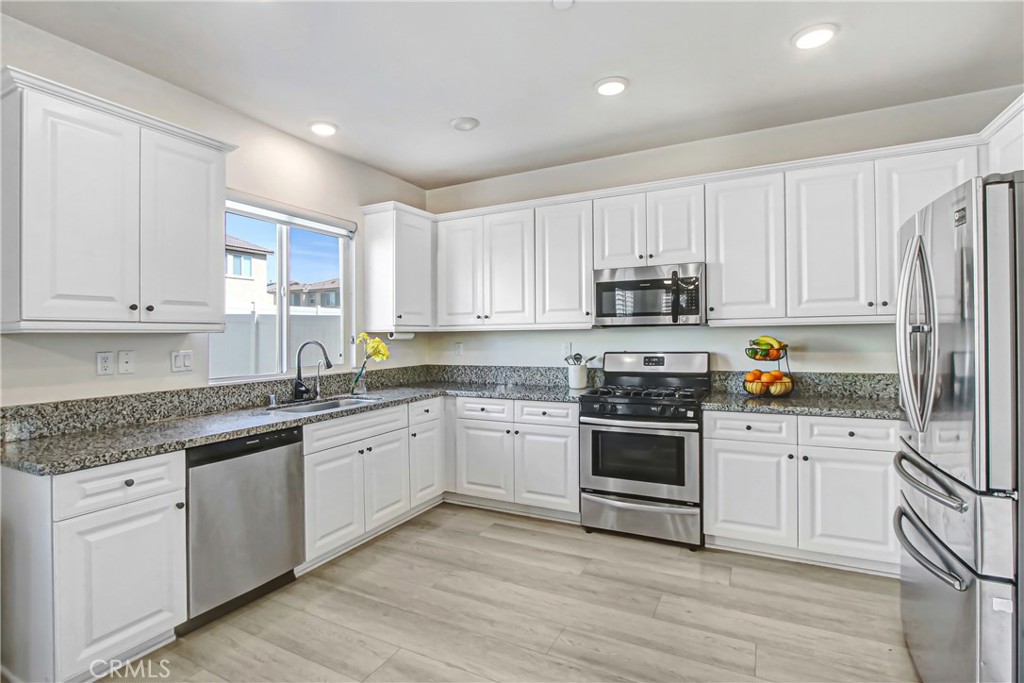 11079 Longfield Lane Eastvale, CA 91752 - Photo 7 of 16 a kitchen with granite countertop white cabinets and stainless steel appliances