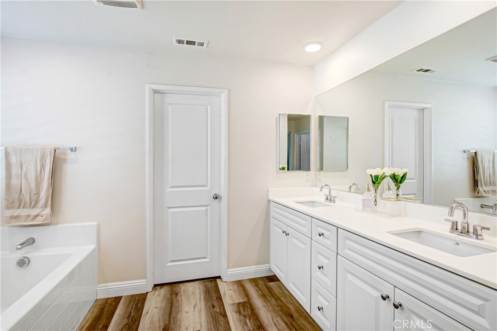 11079 Longfield Lane Eastvale, CA 91752 - Photo 10 of 16 a spacious bathroom with a double vanity sink a mirror and a bathtub