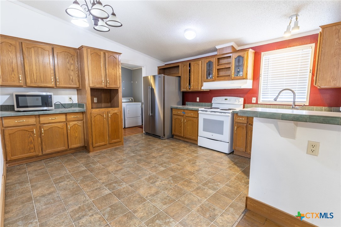 5526 Farm To Market 20 Seguin, TX 78155 - Photo 8 of 18 a kitchen with stainless steel appliances granite countertop a sink a stove top oven a chimney cabinets and a refrigerator