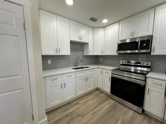 a kitchen with stainless steel appliances granite countertop a stove a sink and a microwave