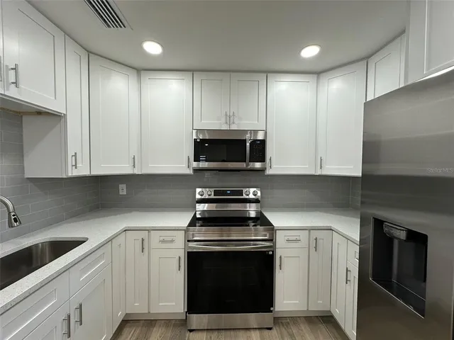 a kitchen with granite countertop white cabinets and stainless steel appliances