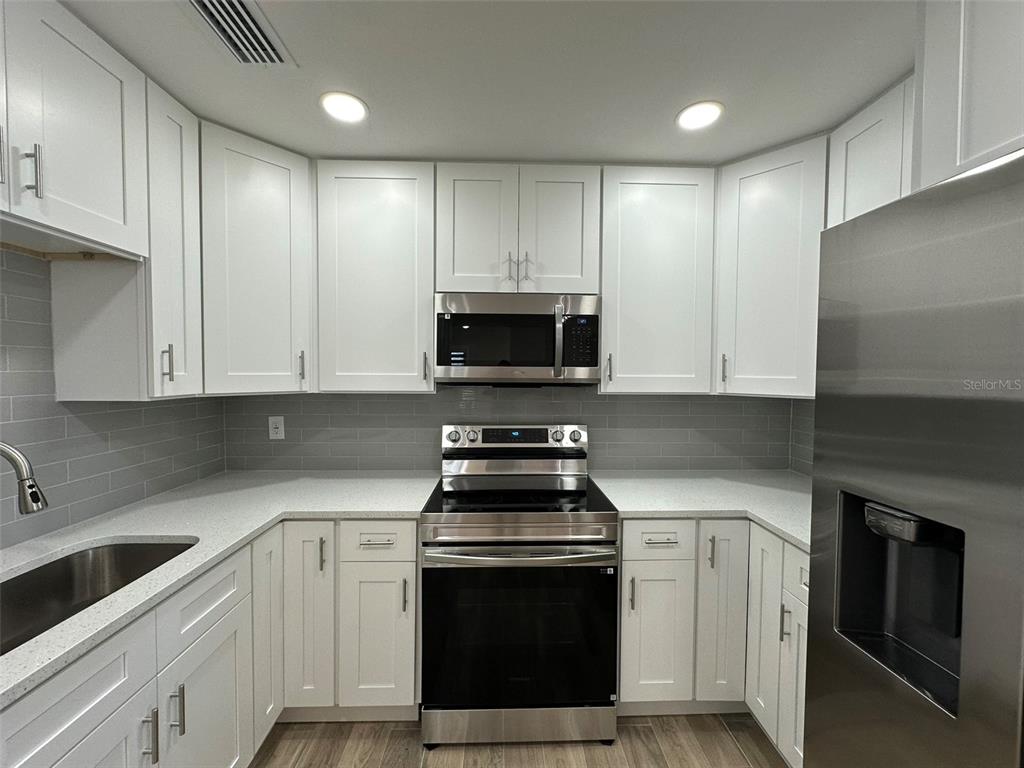 6013 Fortune Place, Unit 6013 Apollo Beach, FL 33572 - Photo 15 of 38 a kitchen with granite countertop white cabinets and stainless steel appliances