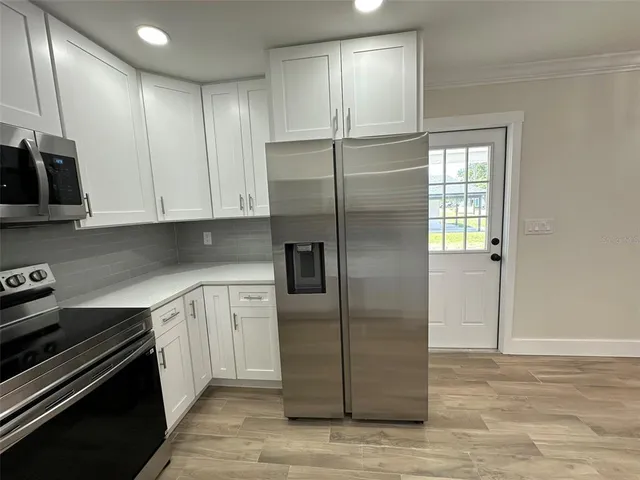 a kitchen with stainless steel appliances granite countertop a refrigerator a stove and a sink with wooden cabinets