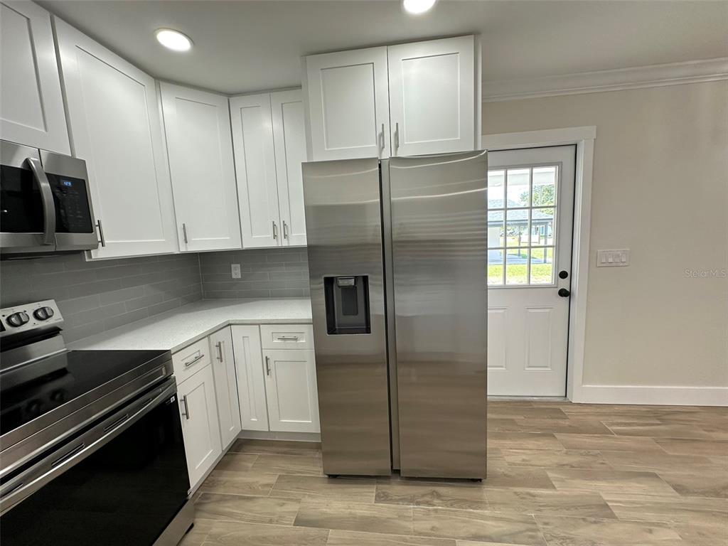 6013 Fortune Place, Unit 6013 Apollo Beach, FL 33572 - Photo 17 of 38 a kitchen with stainless steel appliances granite countertop a refrigerator a stove and a sink with wooden cabinets