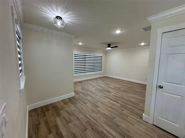 a view of empty room with wooden floor and fan