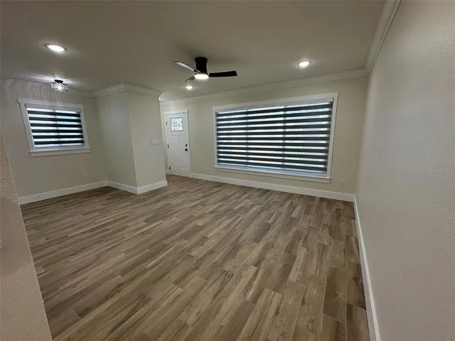 an empty room with wooden floor and windows
