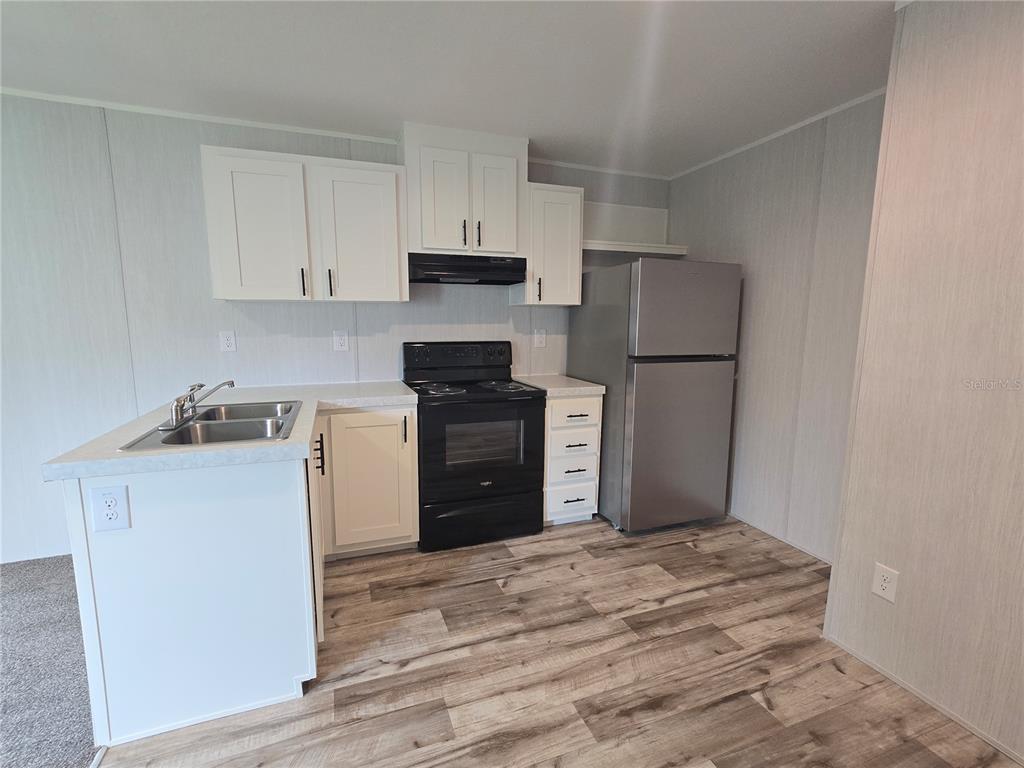 24048 Ermine Road Astor, FL 32102 - Photo 11 of 20 a kitchen with a refrigerator and a stove top oven