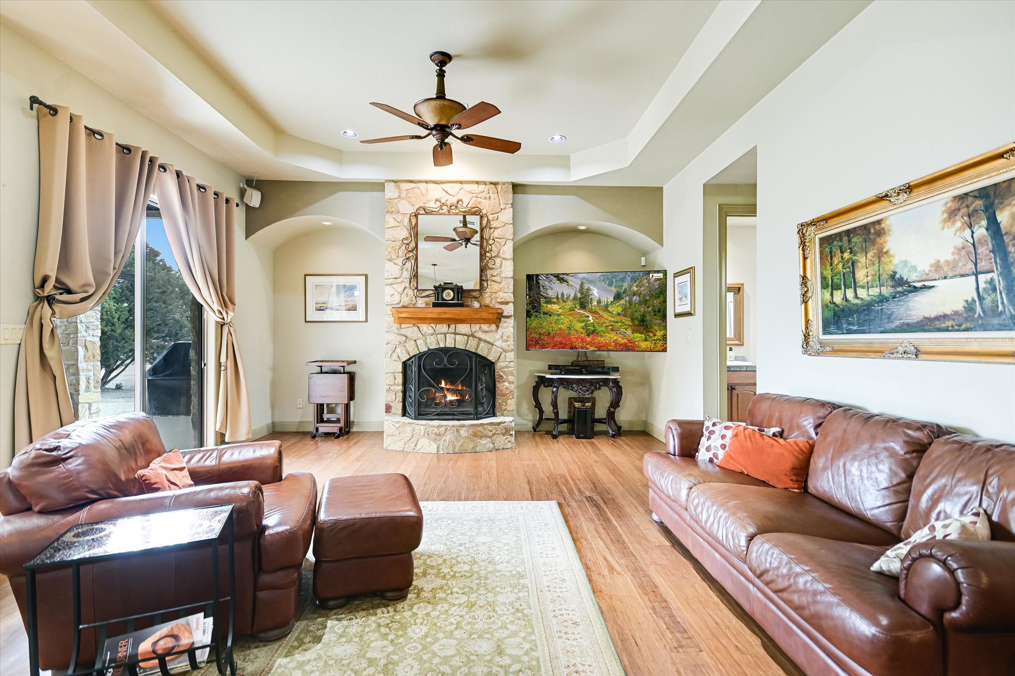 117 View Drive Georgetown, TX 78628 - Photo 12 of 40 Family room with a ceiling fan, light wood flooring, a stone fireplace, a raised ceiling, and recessed lighting