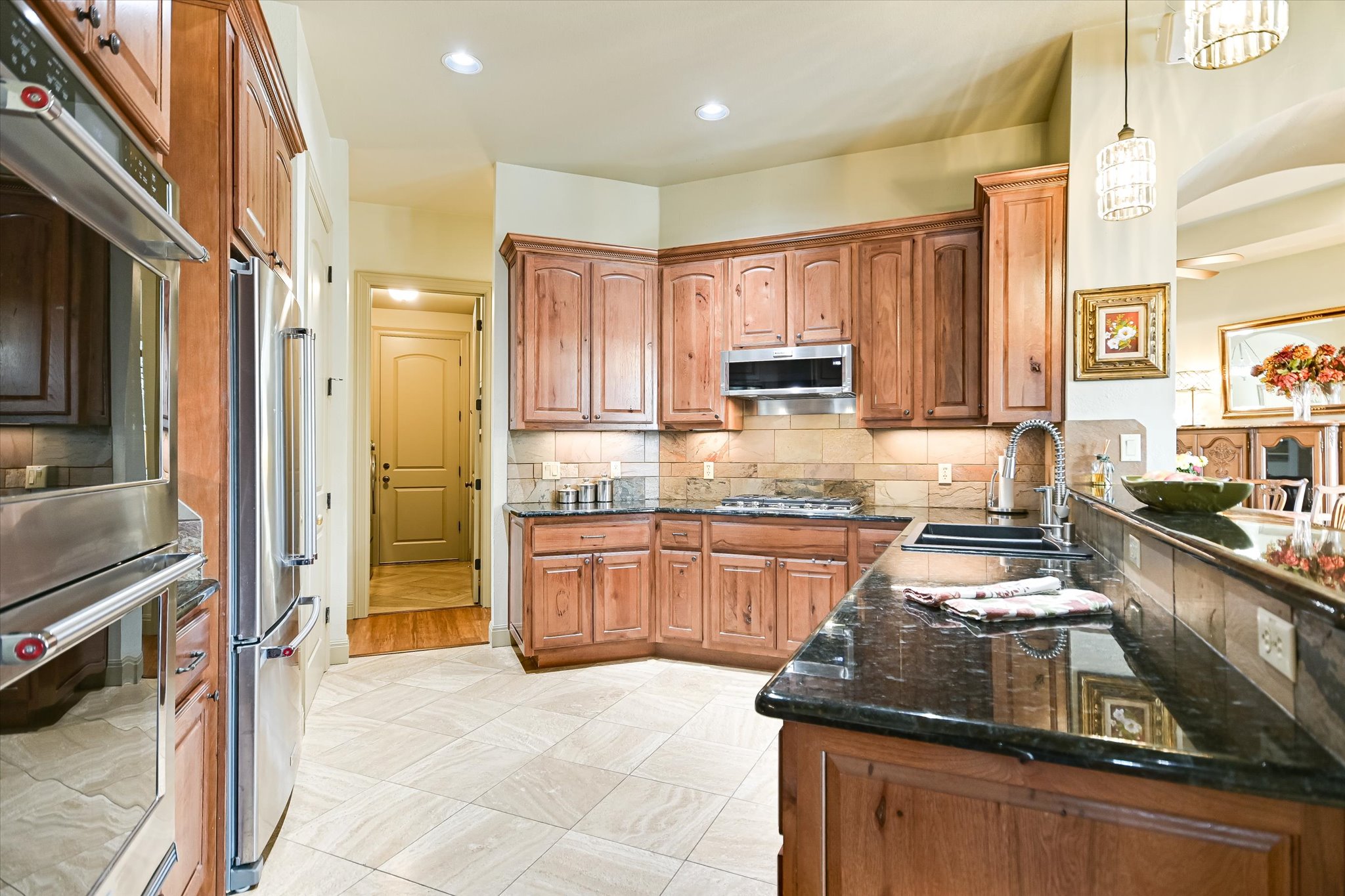 117 View Drive Georgetown, TX 78628 - Photo 15 of 40 Kitchen featuring wood cabinetry, stainless steel Kitchenaid appliances, dark granite countertops, slate backsplash, double ovens with one of them being a convection oven.