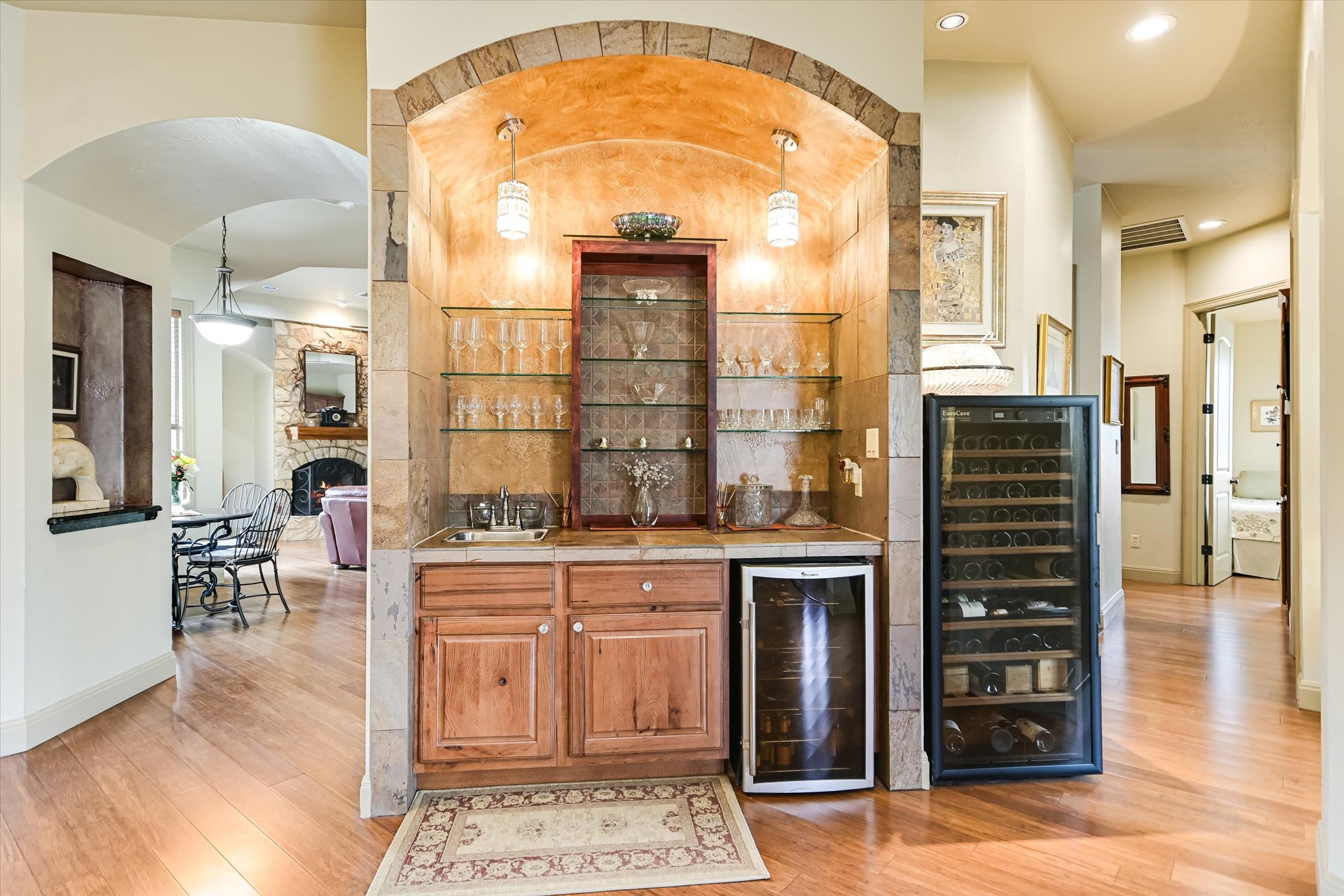 117 View Drive Georgetown, TX 78628 - Photo 10 of 40 Indoor wet bar featuring beverage cooler, a stone alcove, light wood flooring, and hanging light fixtures