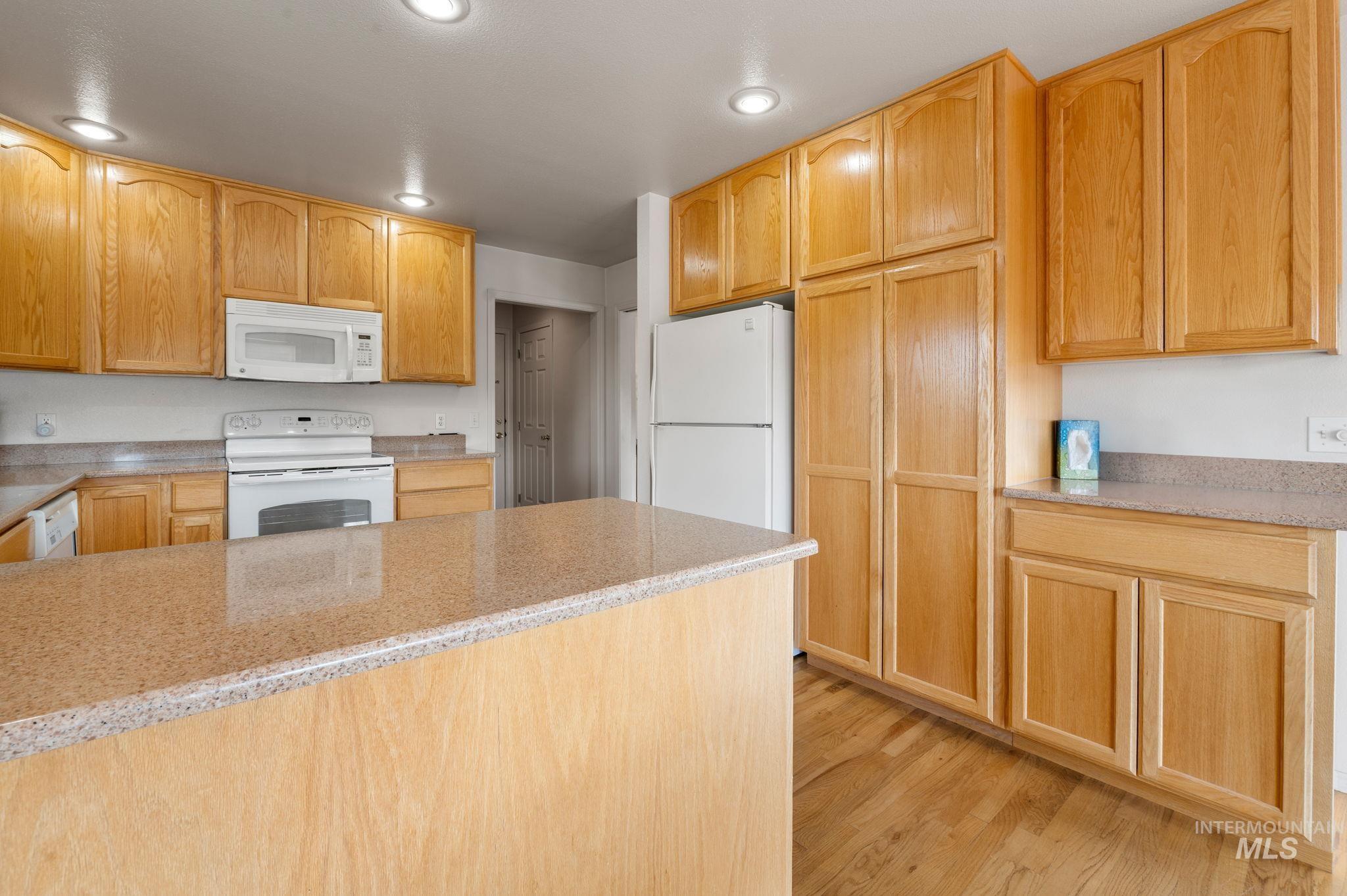 824 15th Avenue Lewiston, ID 83501 - Photo 11 of 37 Kitchen featuring white appliances, light wood-type flooring, recessed lighting, and light stone counters
