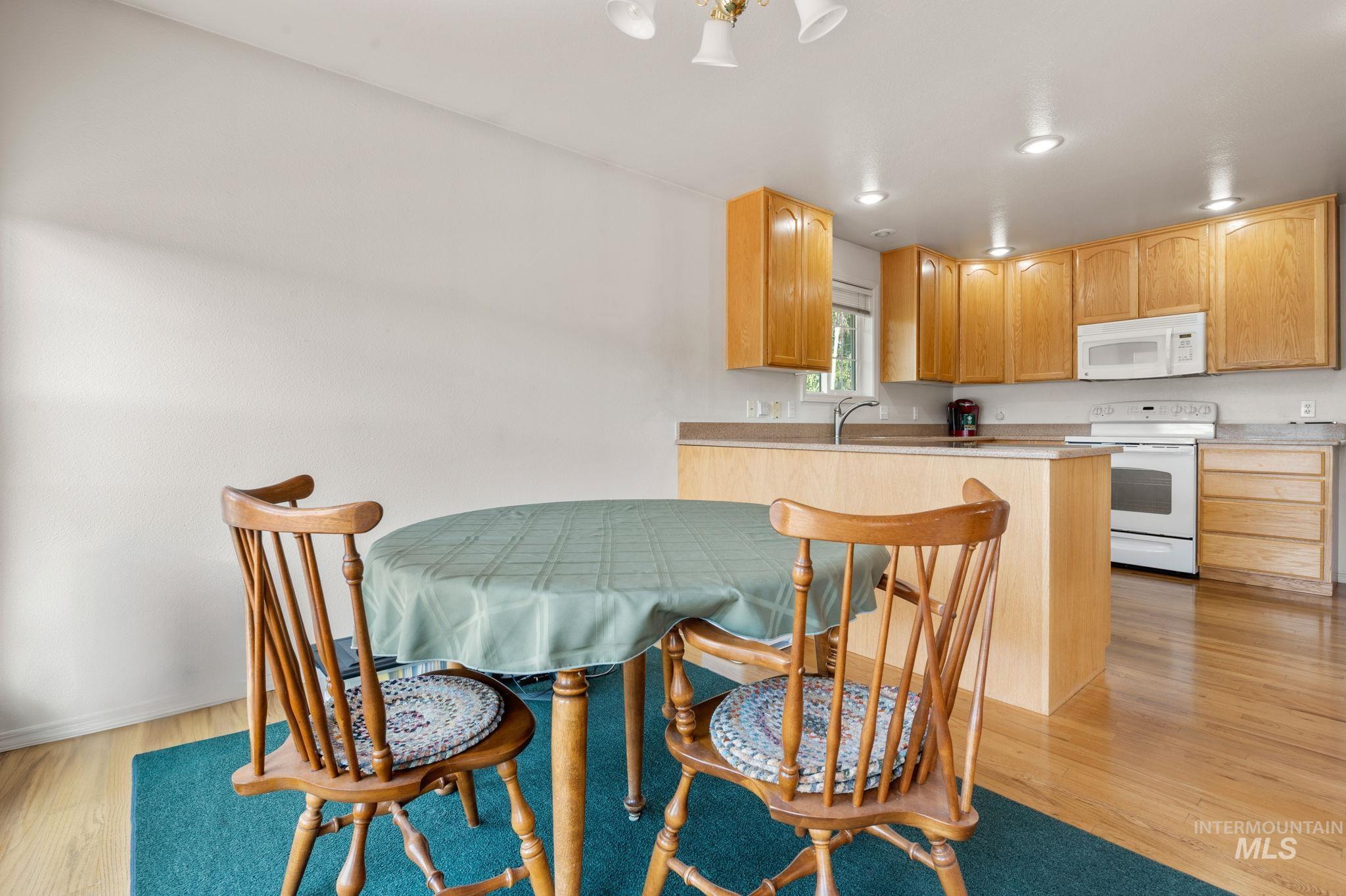 824 15th Avenue Lewiston, ID 83501 - Photo 8 of 37 Kitchen featuring white appliances, light wood-type flooring, a peninsula, a kitchen breakfast bar, and recessed lighting