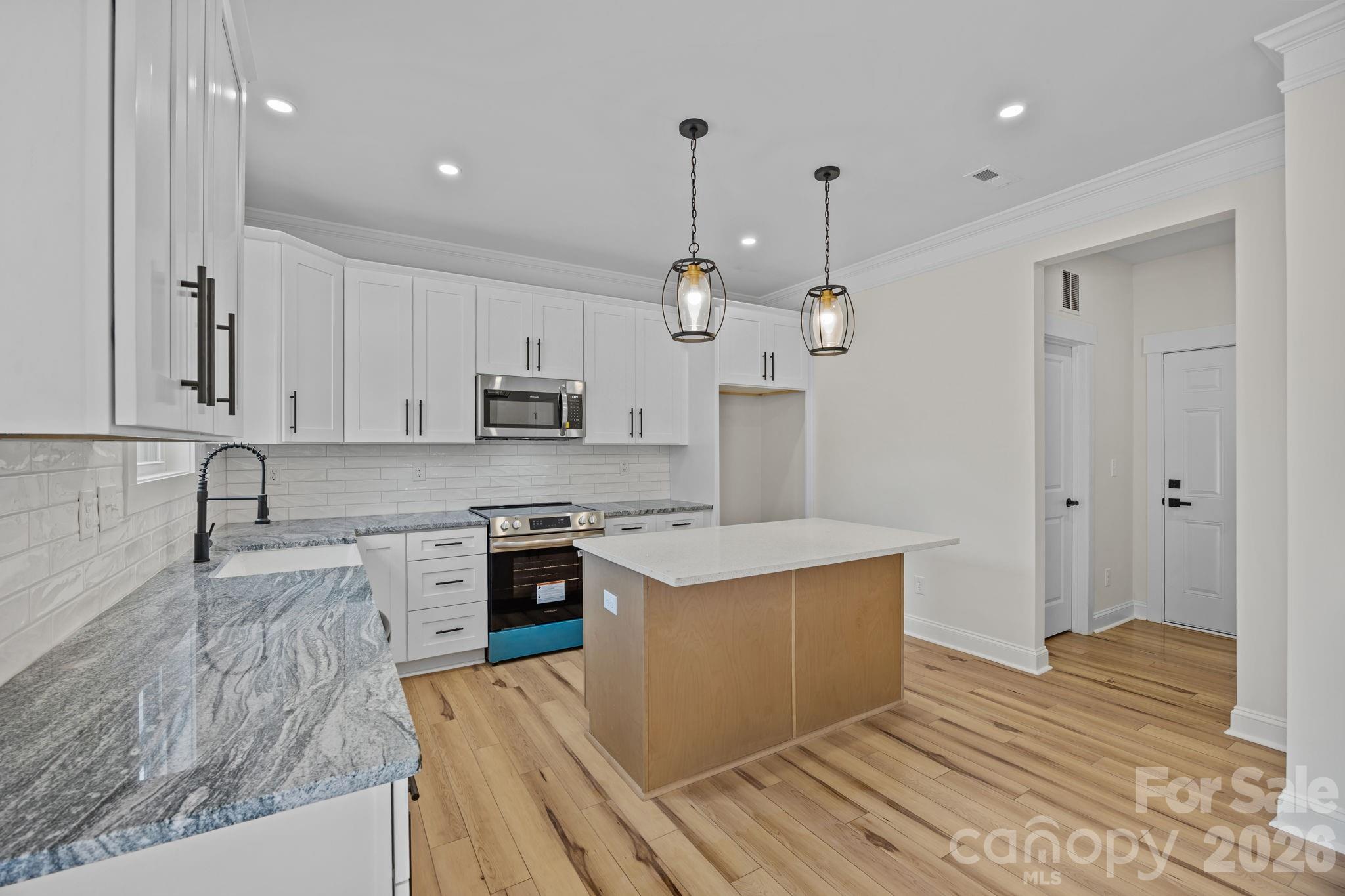 1050 Gibson Road Salisbury, NC 28147 - Photo 21 of 47 a large kitchen with stainless steel appliances granite countertop a stove a sink dishwasher and a refrigerator with wooden floor