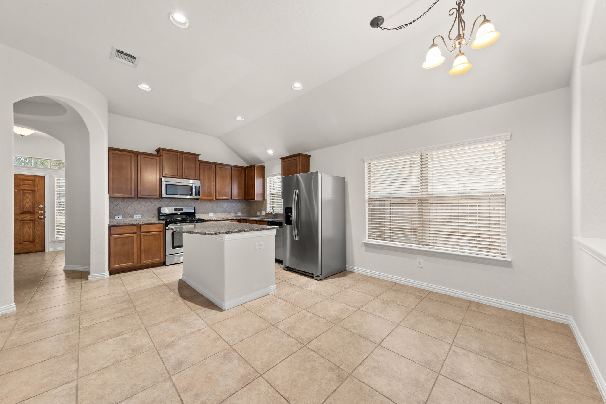 411 Tascate Street Georgetown, TX 78628 - Photo 16 of 41 A well-equipped kitchen features a functional island and durable tile flooring, perfect for daily living.