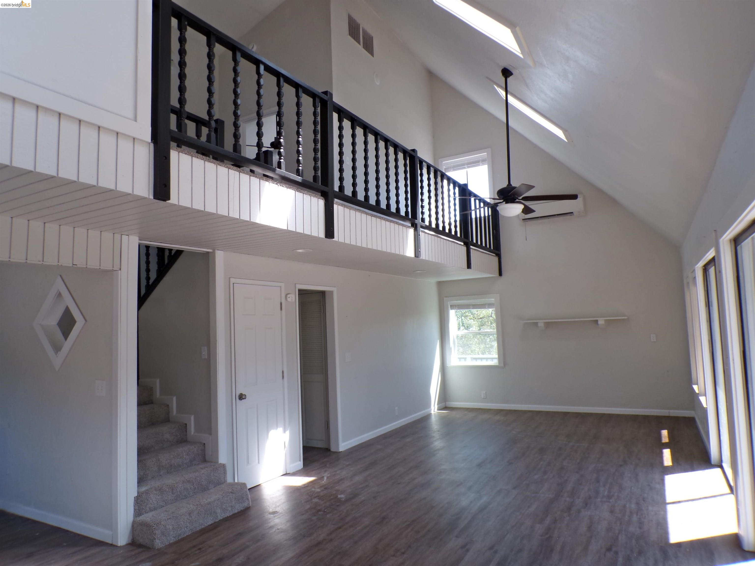 4271 Council Trail Copperopolis, CA 95228 - Photo 11 of 32 Open-concept living space featuring vaulted ceilings, wood-finish flooring, and a second-story balcony with dark wood balusters