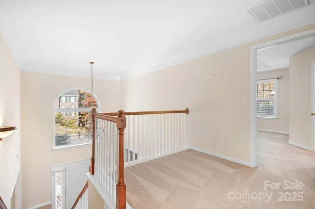 a view of a hallway to a bedroom with wooden floor & windows