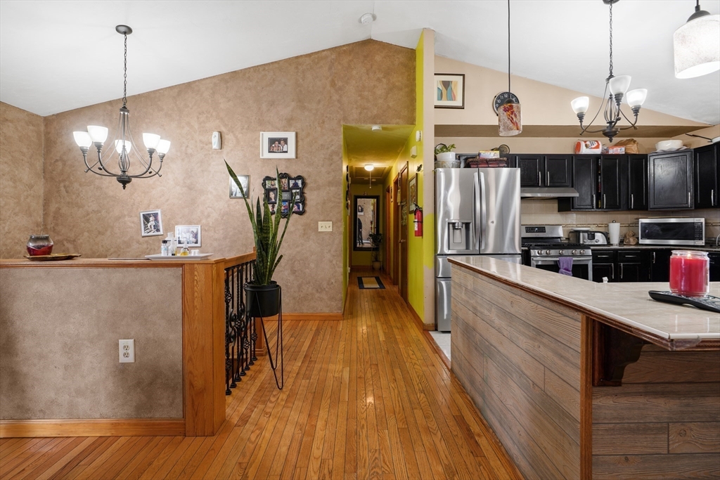 76 Price Place Fall River, MA 02724 - Photo 3 of 27 a view of a kitchen with stainless steel appliances granite countertop a refrigerator a stove and a sink with wooden floor