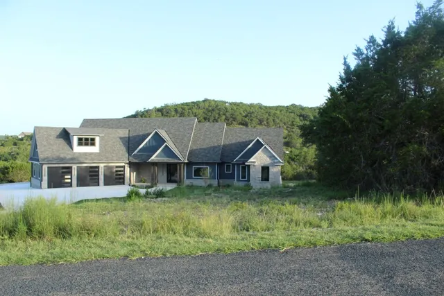 a view of a house with a big yard and large trees